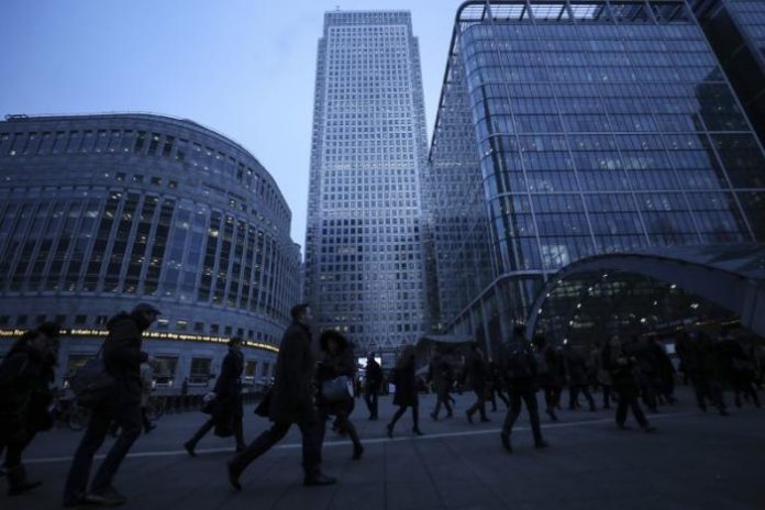 Workers walk to work during the morning rush hour in the financial district of Canary Wharf in London