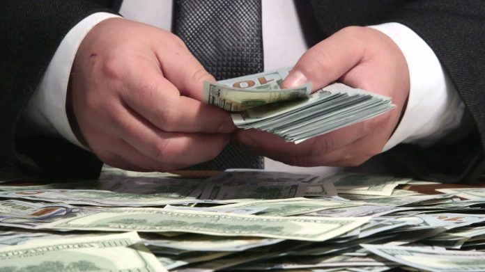 business-person-counting-bundle-of-us-100-dollars-