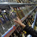 A customer takes a bottle of vodka from a shelf in a Russian supermarket in Benidorm