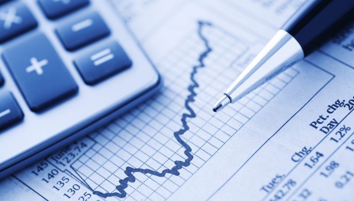 Close-up of a Calculator and Pen on a Financial Newspaper. Blue-toned.
