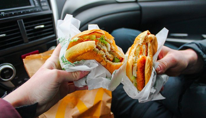 Cropped Image Of Hands Holding Hamburger In Car