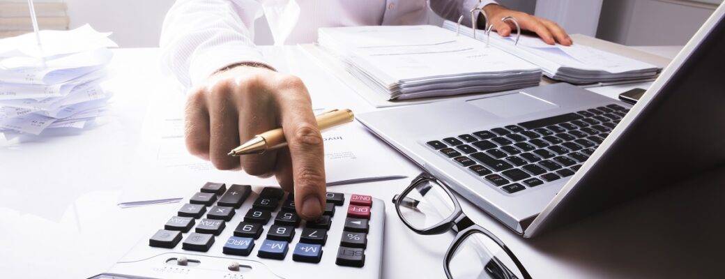 businessman calculating tax using calculator 1200x800 1 1040x400 1